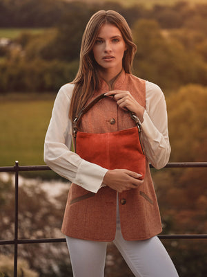 women holding our mini tetbury tote bag in sunset orange, while wearing the Madeline gilet in coral .